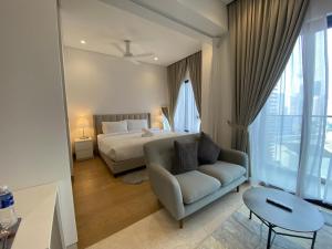 a bedroom with a bed and a couch and a table at Lalaport Suites At Lucentia Bukit Bintang City Center in Kuala Lumpur