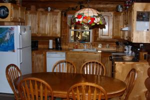 a kitchen with a table and chairs and a refrigerator at Wise Old Hunter Lodge in Anchor Point