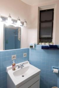 a blue tiled bathroom with a sink and a mirror at Warm 1-Bedroom Apt in Manhattan in New York