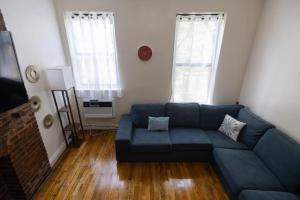 a living room with a blue couch and two windows at Warm 1-Bedroom Apt in Manhattan in New York