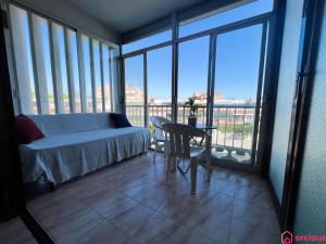 - une chambre avec un lit, une table et des fenêtres en verre dans l'établissement Oasis a 50m del Mar, à Grao de Castellón
