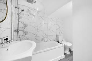 a white bathroom with a tub and a toilet at Cool 2 Bed Basement Flat in Central Shoreditch! in London