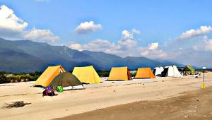 a row of tents on a beach with mountains in the background at Mr. B's Place in Bhurkīā
