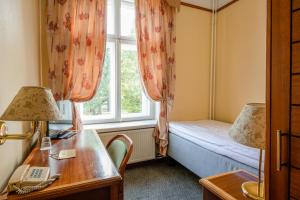 Habitación con cama, escritorio y ventana. en Hotel Victoria, en Pärnu