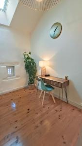 Zimmer mit einem Schreibtisch, einem Stuhl und einer Uhr in der Unterkunft Le gîte de Varanges maison de ville au coeur de Givry classée 3 étoiles in Givry