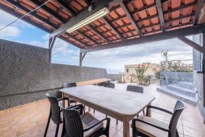 a table and chairs on a patio with a roof at Sun View House by GALMI in Ribeira Brava
