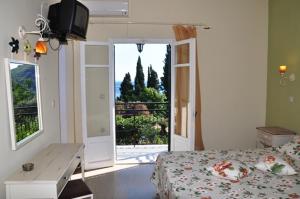 a bedroom with a bed and a desk and a window at Taxi Driver Apartments in Paleokastritsa