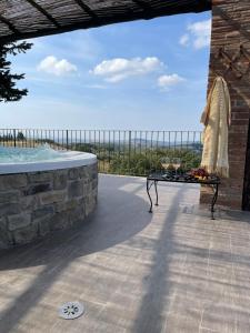 a patio with a hot tub and a table with a view at Castellare Di Tonda Tuscany Country Resort & Spa in Montaione
