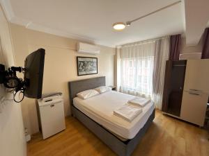 Un dormitorio con una cama y un televisor. en Meydan Pansiyon Uskudar, en Estambul
