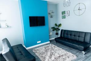een woonkamer met een zwarte bank en een blauwe muur bij Emerald Gem of Leeds with Great Location including Parking in Killingbeck