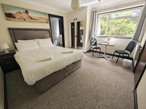 Little Foxes Hotel & Gatwick Airport Parking في كراولي: غرفة نوم بسرير كبير وطاولة وكراسي