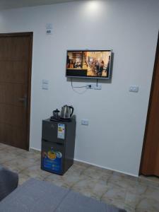 a tv on a white wall with a refrigerator at Petra Midtown hostel in Wadi Musa +4 photos