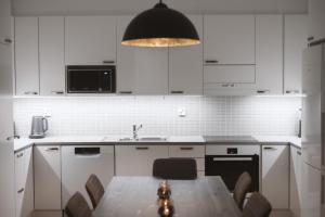 ロヴァニエミにあるApartment Mallaの白いキャビネットとテーブルと椅子のあるキッチン