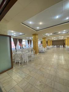 un salón de banquetes con mesas y sillas blancas y una pantalla en Hotel Diana, en Bistriţa