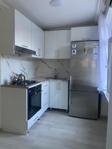 eine Küche mit weißen Schränken und einem Kühlschrank aus Edelstahl in der Unterkunft Happy home Narimanov in Baku