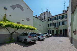 dos coches estacionados en un estacionamiento junto a los edificios en A Casa Dei Gonzaga, en Mantua