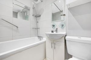 a white bathroom with a sink and a toilet and a bath tub at Charming 3 Bedroom House near Canary Wharf in London