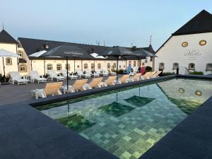 a hotel swimming pool with chairs and a building at Chateau d'Urspelt in Urspelt