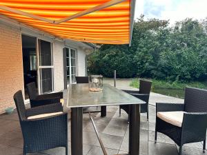 a table and chairs on a patio with an orange canopy at Ferienhaus Brombeerhof in Munkbrarup