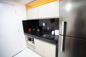 a kitchen with a stainless steel refrigerator and white cabinets at Unity Beira Mar de João Pessoa by Carpediem in Penha
