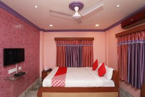 sypialnia z łóżkiem z czerwonymi ścianami i telewizorem w obiekcie OYO Flagship Rainbow Guest House w mieście Jādabpur