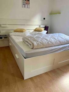 a large white bed in a room with wooden floors at Coralline, Appartement lumineux à 2 pas de la mer. in Wimereux