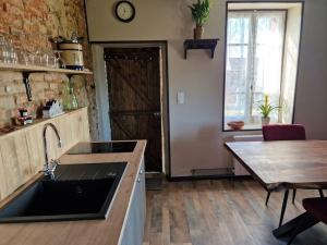 cocina con fregadero, mesa y puerta en Gite La Maison Des Trois Grands, en Sannat