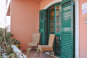 um pátio com 2 cadeiras e uma porta verde em Supertubos Beach Villa em Atouguia da Baleia