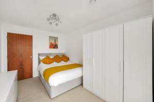 a white bedroom with a bed with orange pillows at Entire Apartment in the heart of Canary Wharf! in London
