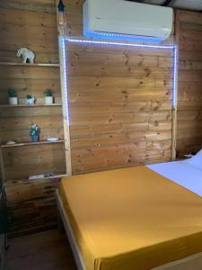 1 dormitorio con 1 cama con pared de madera en Cabane des Zamoureux en Ducos