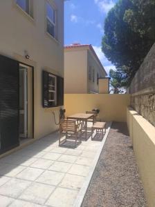 un patio con tavolo e panche accanto a un edificio di Casa das Lombas a Vila Baleira
