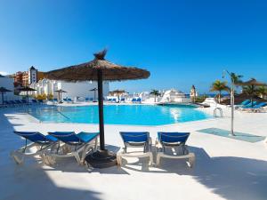 a table with chairs and an umbrella next to a swimming pool at Idaira Paradise in Playa Paraiso