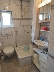 uma casa de banho com um WC, um lavatório e uma banheira em Apartments Carmen em Braunlage