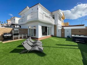 Una casa con césped con sillas. en Villa Sofía Maspalomas, en San Bartolomé