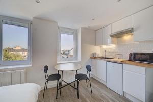 a kitchen with a table and chairs in a room at L'Espadon - Appart'Escale in Saint-Nazaire