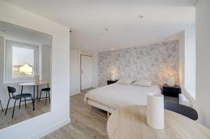 a bedroom with a bed and a table and chairs at L'Espadon - Appart'Escale in Saint-Nazaire