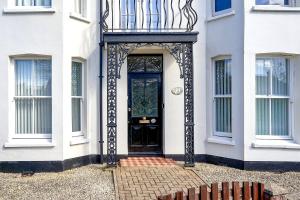 une porte noire sur une maison blanche dans l'établissement Hurn Crag House, Stunning ground floor apartment near Southwold, à Southwold