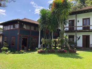 a house with palm trees in front of a yard at Casa Temporada com Tranquilidade e Aconchego - Petrópolis - RJ in Petrópolis