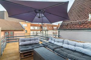 a patio with two couches and an umbrella on a balcony at Unique Apartments Wiesloch in Wiesloch