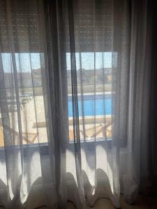 a window with white curtains with a view of a pool at Elia Residence Rooms in Bečići