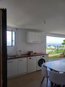 a kitchen with white cabinets and a table and a window at Kazpucins T2 vue mer et pitons in Les Trois-Îlets