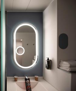 bagno con specchio rotondo e lavandino di ibis Paris Gare de Lyon Reuilly a Parigi