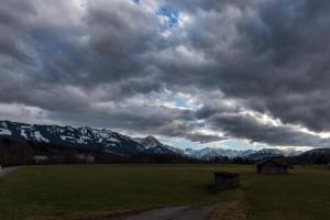 a green field with a cloudy sky and mountains at Ferienwohnung Kupfer in Sonthofen