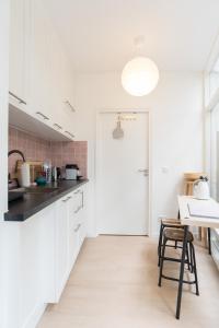 a kitchen with white cabinets and a table and a door at B&B Amsterdam West in Amsterdam