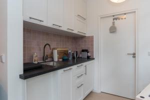 a kitchen with white cabinets and a sink at B&B Amsterdam West in Amsterdam
