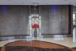 Premium 1BHK near Metro station Dubai Marina & JBR في دبي: غرفة مع مزهرية مع الزهور الحمراء فيها