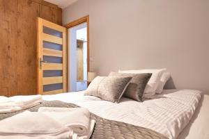 a bedroom with a large bed with white sheets and pillows at Apartamenty Widokowe Pod Lasem in Kościelisko