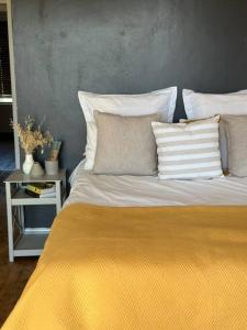 a bed with a yellow blanket and pillows on it at Clarens Tranquil Mountain Villa in Clarens