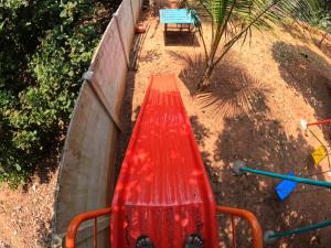 a red bench sitting next to a wall at Wow Farm House in Auroville
