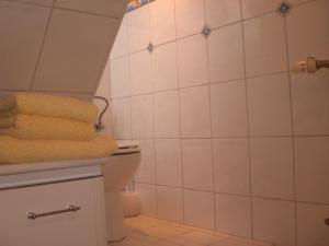 a bathroom with a toilet and white tiled walls at Gästehaus Wolf in Sierksdorf